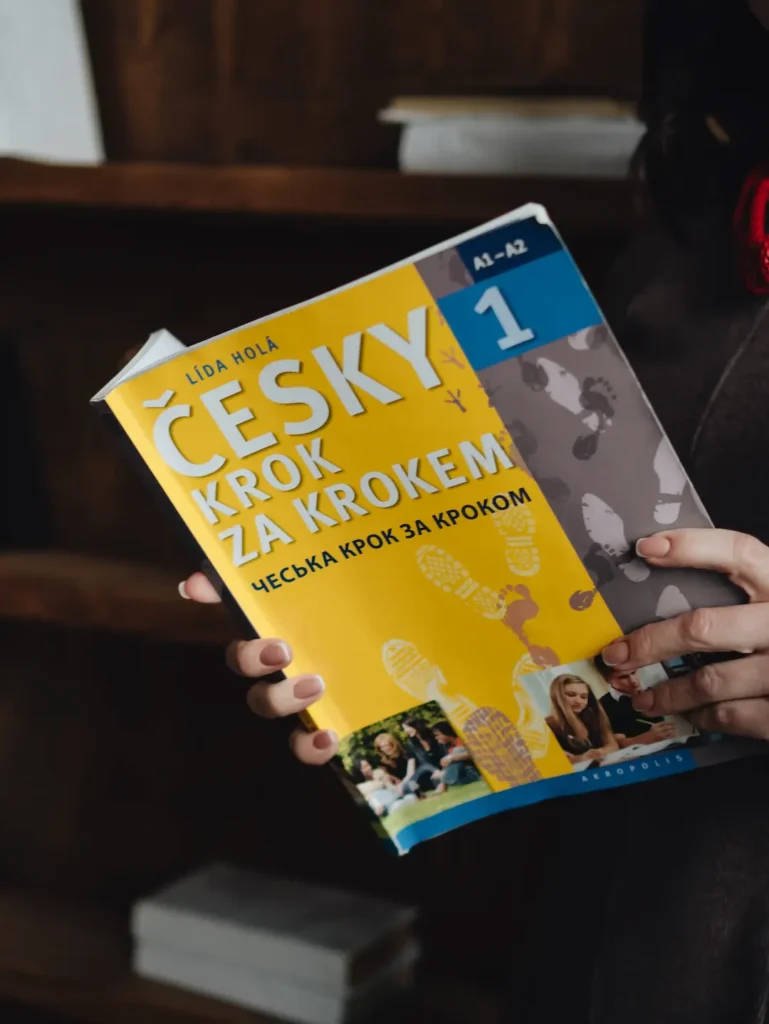 людина тримає підручник чеської мови A1-A2 для підготовки до вступу